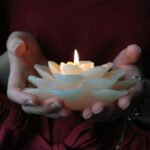 hands holding a lotus flower candle